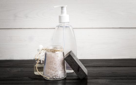 Spa still life. Aroma oils, stones, soap, sea salt and shampoo on wooden background. Various bath accessories. Items for the spa. Copy space