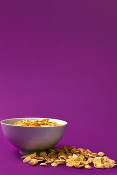 Bowl with cornflakes on the colorful background. Purple background. Copy space. Still life. Flat lay