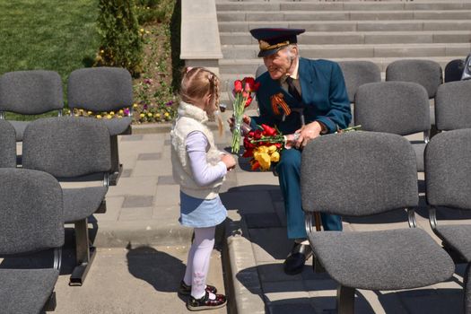 PYATIGORSK, RUSSIA - MAY 09, 2011: Girl gives flowers to veteran on Victory Day