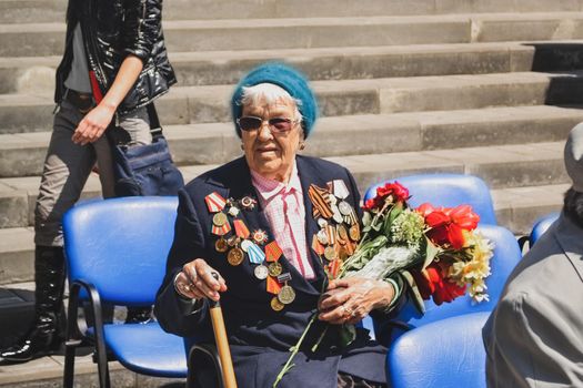 PYATIGORSK, RUSSIA - MAY 09, 2011: War veteran woman with flowers on the Victory Day celebration. Russian babushka