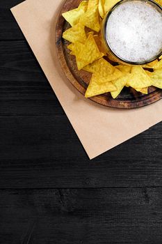 Glass of beer with nachos chips on a wooden background. Top view. Copy space. Still life. Flat lay