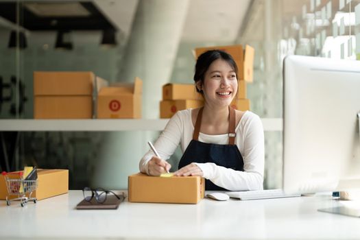 Starting Small business entrepreneur freelance, Portrait young asian woman working at home office with computer, online, marketing, packaging, delivery, SME, e-commerce concept.