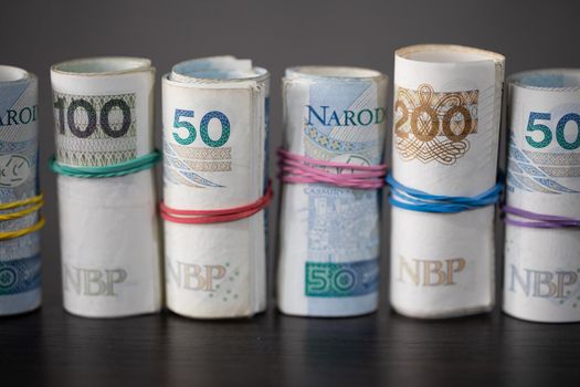 Savings rolled up and displayed on a table. Poland's national paper cash. Banknotes rolled up and tied together with a rubber band.