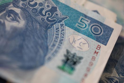 A thick bundle of paper money compressed with a red rubber band. Polish national paper cash.