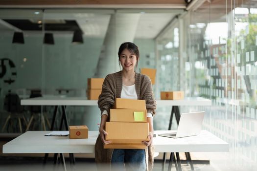 Starting small businesses SME owners female entrepreneurs holding stack of box to review orders online to prepare to pack boxes, sell to customers, online sme business ideas