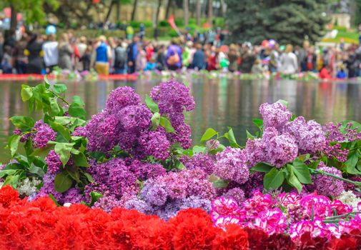 Red carnations and lilacs on a marble military memorial near water
