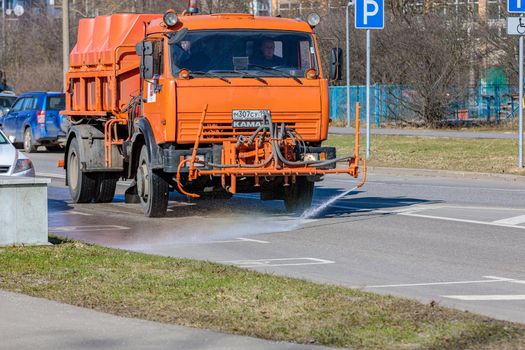 A transport service car washes the road with water from a hose. The machine washes away dirt and road dust. Moscow Russia April 14, 2022.