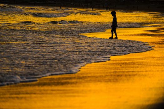Kid playing at dusk waves. Shooting Location: Kamakura City, Kanagawa Prefecture