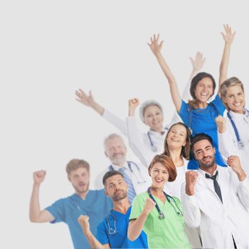Medical team of male and female doctors and nurses celebrating with arms raised isolated on gray background corner frame design element copy space for text