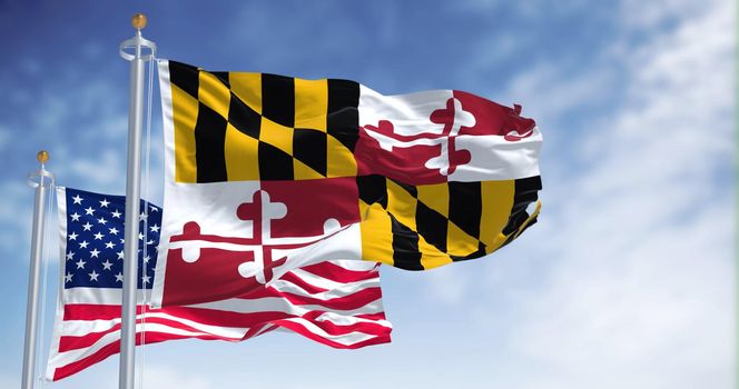 The Maryland state flag waving along with the national flag of the United States of America. In the background there is a clear sky. Maryland is a state in the Mid-Atlantic region of the United States