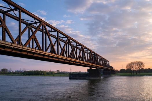 Old bridge crossing the Rhine river, sunset at Rhinepark, Duisburg, Germany