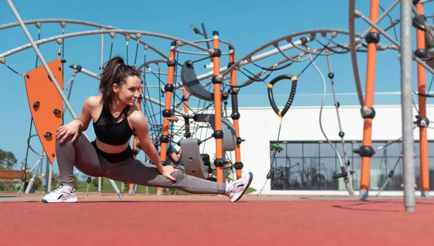 sporty girl does fitness on a sports field in the summer outdoors