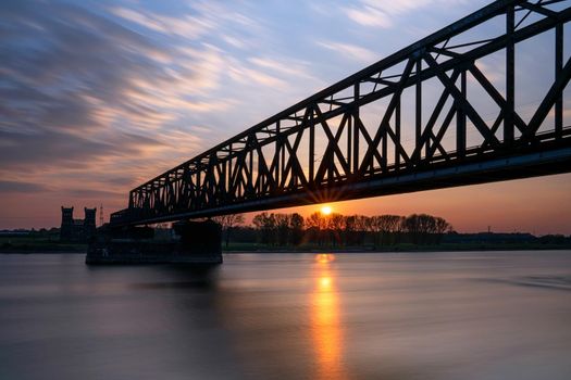 Old bridge crossing the Rhine river, sunset at Rhinepark, Duisburg, Germany