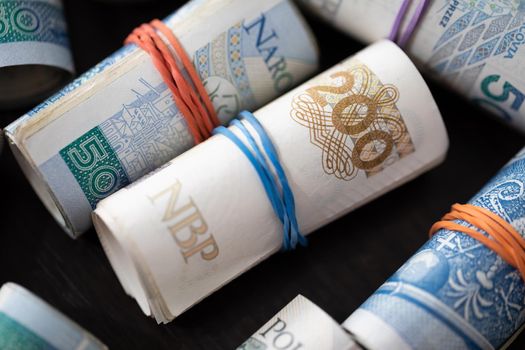 A frame from very close up. Several rolls of Polish banknotes in an overhead view. Rolled up and tied with a rubber band.