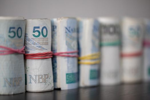 Oblique view of several rolls of fifty and one hundred zloty banknotes. Poland's national paper cash.