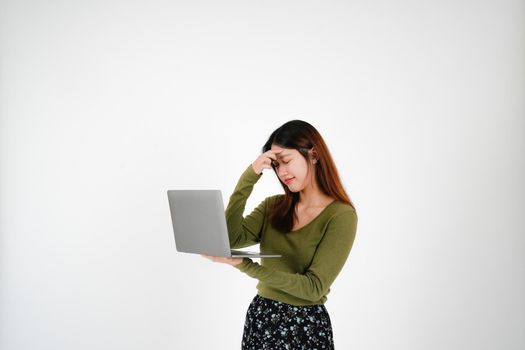 Headache young asian woman is holding laptop computer on white Studio background - seriously pose.