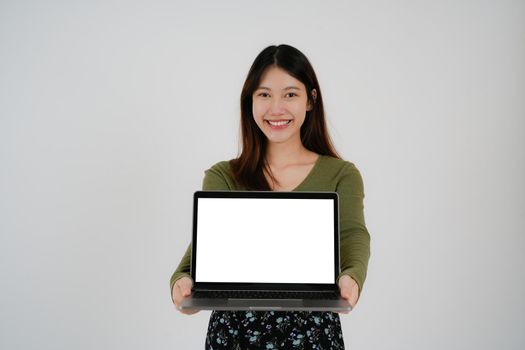 young asian girl holding a laptop and show blank white sreen, isolated on white background.