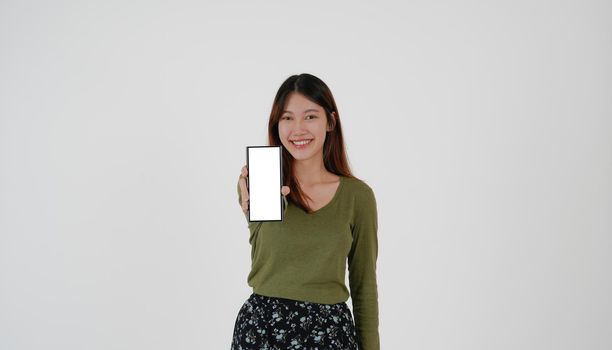 Image of young asian girl holding smartphone show blank white screen on white background