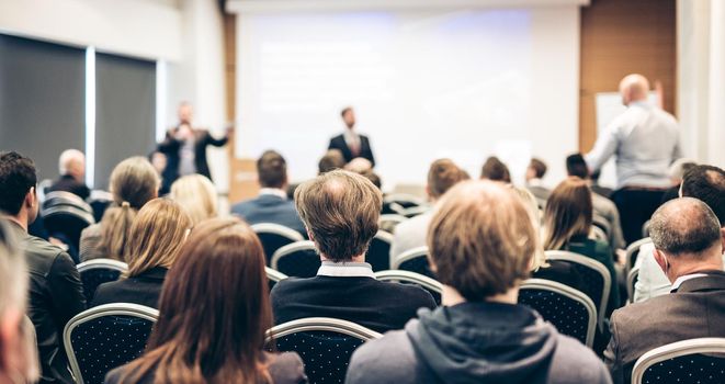 I have a question. Group of business people sitting at the chairs in conference hall. Businessman standing up asking a question. Conference and Presentation. Business and Entrepreneurship.