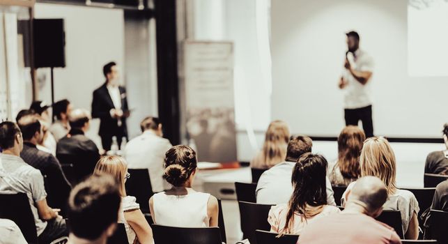 Speaker giving a talk in conference hall at business event. Rear view of unrecognizable people in audience at the conference hall. Business and entrepreneurship concept.