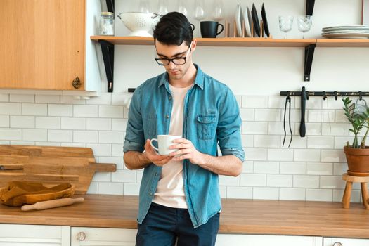 Only awakened, thoughtful handsome young man holds a cup and drinks morning coffee