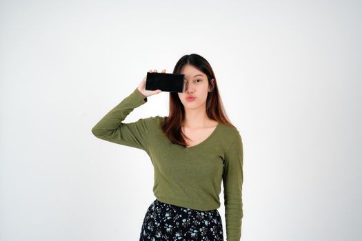 Image of young asian girl holding smartphone show blank white screen on white background