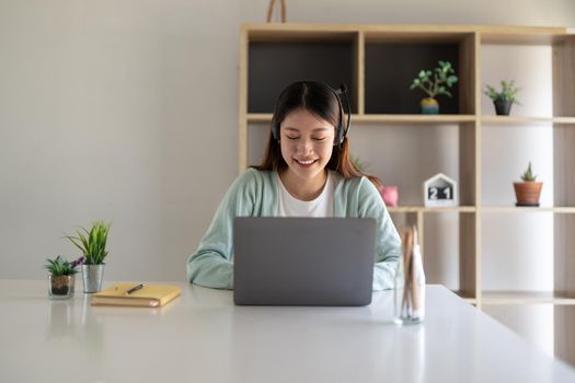 Happy young woman studying online, watching webinar, podcast on laptop. E-learning concept.