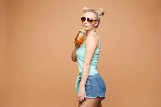 A beautiful woman in a bright outfit, denim shorts in the studio. Summer