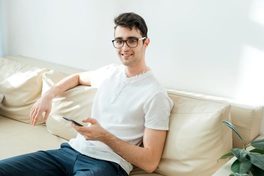 Communication and people concept. A young man looks at the camera and smiles, holding a gadget in his hands