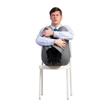 businessman sits in a chair, clasped his knees, isolated over white background