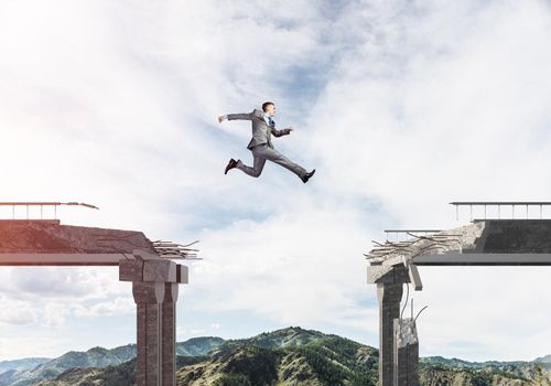 Businessman jumping over huge gap in concrete bridge as symbol of overcoming challenges. Skyscape and nature view on background. 3D rendering.