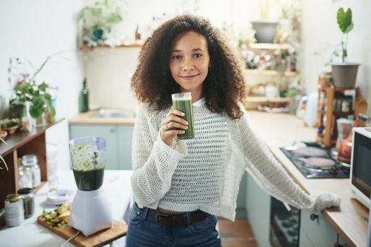 Portrait of you african girl smiling at camera with smoothie in her hand