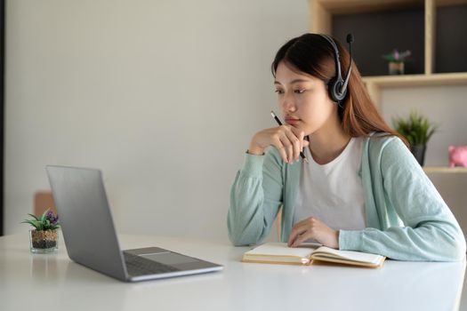 Happy young woman studying online, watching webinar, podcast on laptop. E-learning concept.