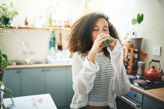 Shot of a beautiful young woman enjoying a healthy green smoothie at home 