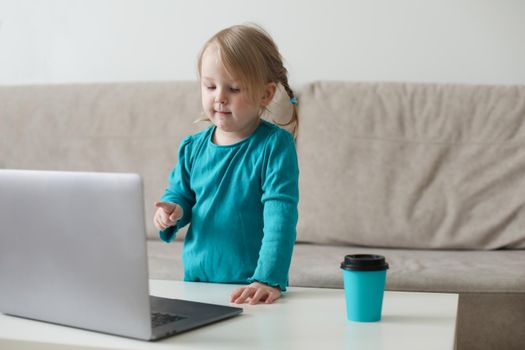 little girl uses a laptop video chat to communicate learning at home, child studying online