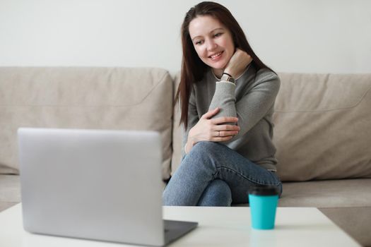 Mother and her daughter using video chat on laptop sitting on cozy sofa at home, watching video