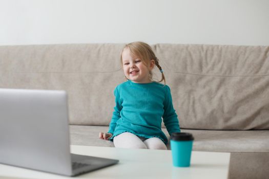 little girl uses a laptop video chat to communicate learning at home, child studying online