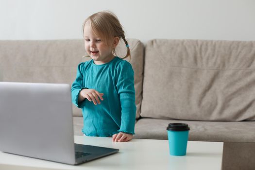 little girl uses a laptop video chat to communicate learning at home, child studying online