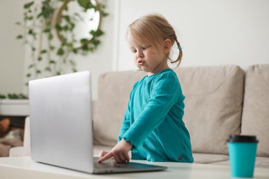 little girl uses a laptop video chat to communicate learning at home, child studying online