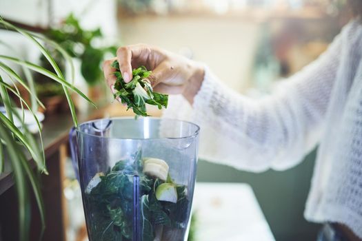 Shot of a young woman making a healthy smoothie at home. High quality photo