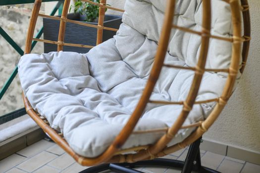 Bamboo chair with grey cushion hanging on the balcony