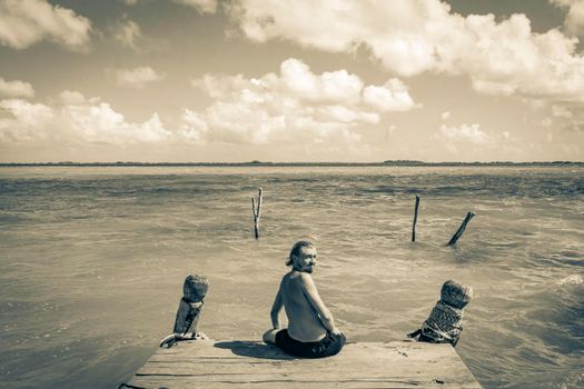 Black and white picture of a traveler and tourist guide on boat jetty pier at the panorama view to the Muyil Lagoon with turquoise water in the tropical jungle Sian Ka'an National park Muyil Mexico.