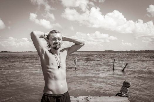 Black and white picture of a traveler and tourist guide on boat jetty pier at the panorama view to the Muyil Lagoon with turquoise water in the tropical jungle Sian Ka'an National park Muyil Mexico.