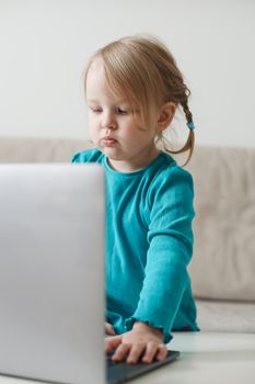 little girl uses a laptop video chat to communicate learning at home, child studying online