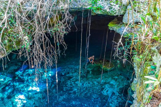 Traveler and tourist guide at amazing blue turquoise water and limestone cave sinkhole cenote Tajma ha Tajmaha in Puerto Aventuras Quintana Roo Mexico.