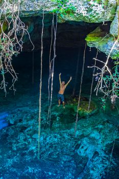 Traveler and tourist guide at amazing blue turquoise water and limestone cave sinkhole cenote Tajma ha Tajmaha in Puerto Aventuras Quintana Roo Mexico.