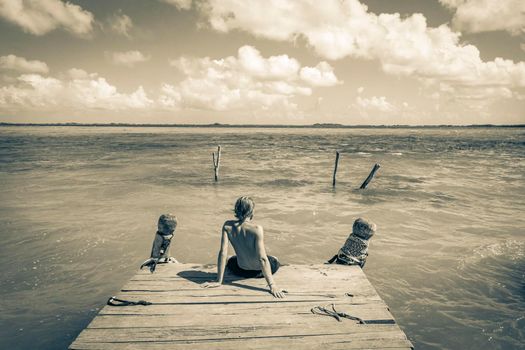 Black and white picture of a traveler and tourist guide on boat jetty pier at the panorama view to the Muyil Lagoon with turquoise water in the tropical jungle Sian Ka'an National park Muyil Mexico.