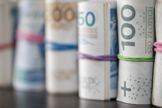 Savings rolled up and displayed on a table. Poland's national paper cash. Banknotes rolled up and tied together with a rubber band.