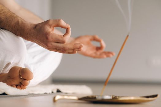 Close-up of a man in white sportswear doing yoga in a fitness room with a balgovon. the concept of a healthy lifestyle.