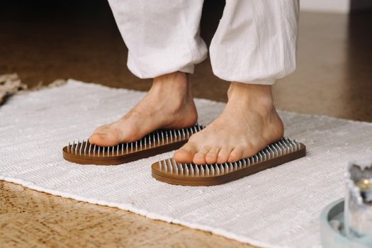 The man's feet are next to boards with nails. Yoga classes.